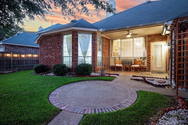 back house at dusk featuring a patio, a yard, and ceiling fan