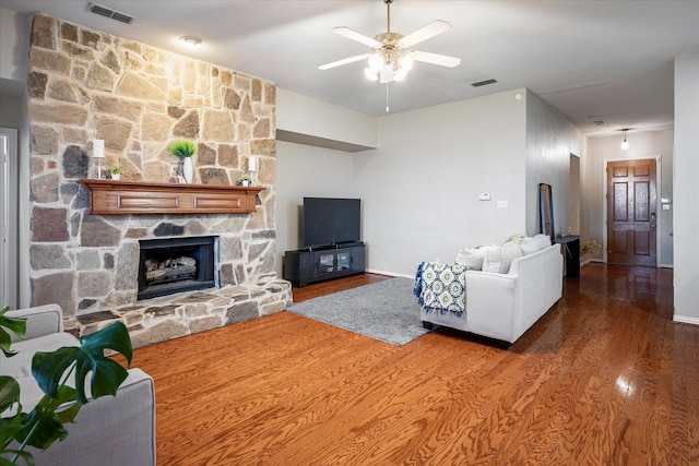 living room featuring a stone fireplace, hardwood / wood-style floors, and ceiling fan