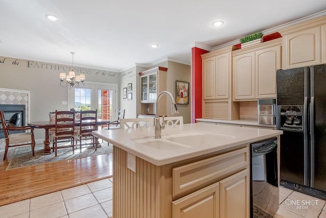 kitchen featuring black appliances, sink, light tile patterned floors, an island with sink, and decorative light fixtures