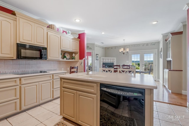 kitchen featuring light tile patterned flooring, an island with sink, sink, decorative backsplash, and black appliances