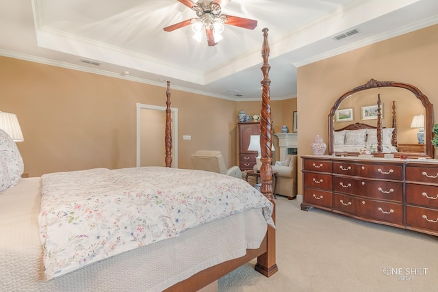 carpeted bedroom with a tray ceiling, ceiling fan, and crown molding