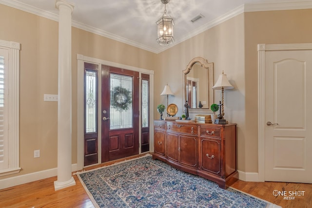 entrance foyer with ornamental molding, a chandelier, light hardwood / wood-style floors, and ornate columns