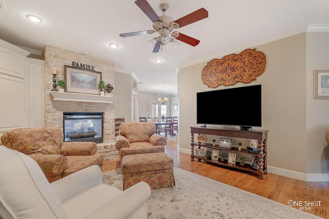 living room featuring a fireplace, ceiling fan with notable chandelier, light hardwood / wood-style floors, and ornamental molding