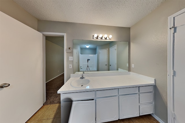 bathroom with tile patterned floors, vanity, and a textured ceiling