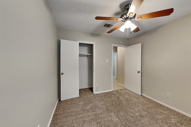 unfurnished bedroom featuring ceiling fan, light colored carpet, a textured ceiling, and a closet