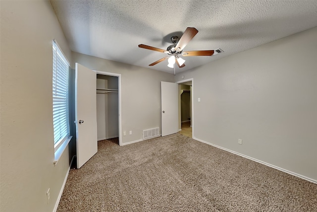 unfurnished bedroom featuring ceiling fan, a textured ceiling, a closet, and carpet flooring