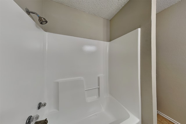 bathroom with shower / tub combination, a textured ceiling, and hardwood / wood-style floors