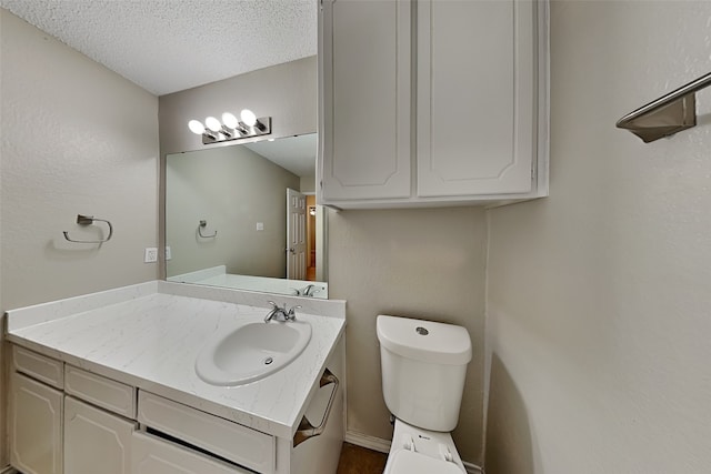 bathroom featuring vanity, toilet, and a textured ceiling