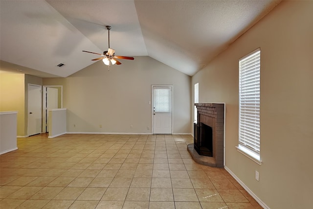 unfurnished living room featuring lofted ceiling, a brick fireplace, ceiling fan, light tile patterned floors, and a textured ceiling