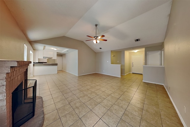 unfurnished living room with a fireplace, vaulted ceiling, light tile patterned floors, and ceiling fan