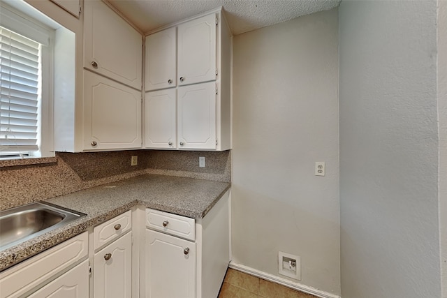 kitchen featuring light tile patterned flooring, sink, a textured ceiling, and white cabinetry