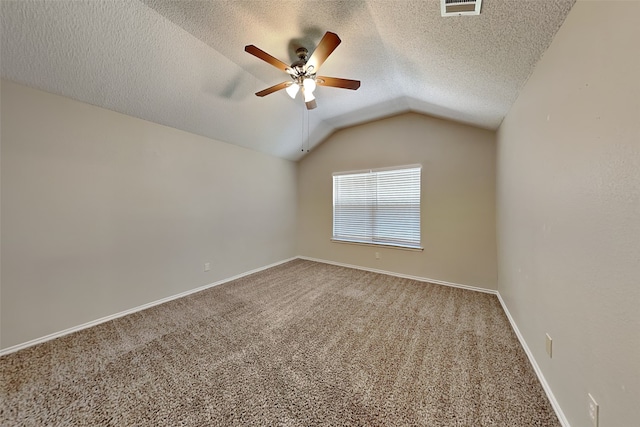 unfurnished room with lofted ceiling, ceiling fan, carpet floors, and a textured ceiling