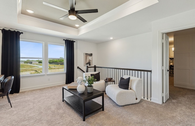 sitting room featuring light carpet, a raised ceiling, and ceiling fan