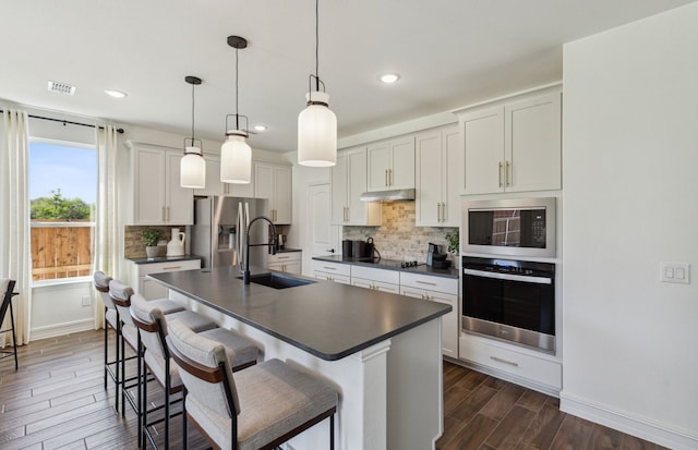 kitchen with decorative light fixtures, sink, stainless steel appliances, backsplash, and white cabinetry