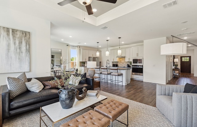 living room with dark wood-type flooring, sink, and ceiling fan