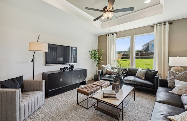 living room with ceiling fan and a tray ceiling