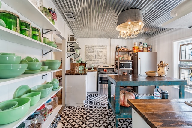 kitchen with an inviting chandelier, stainless steel appliances, and butcher block counters