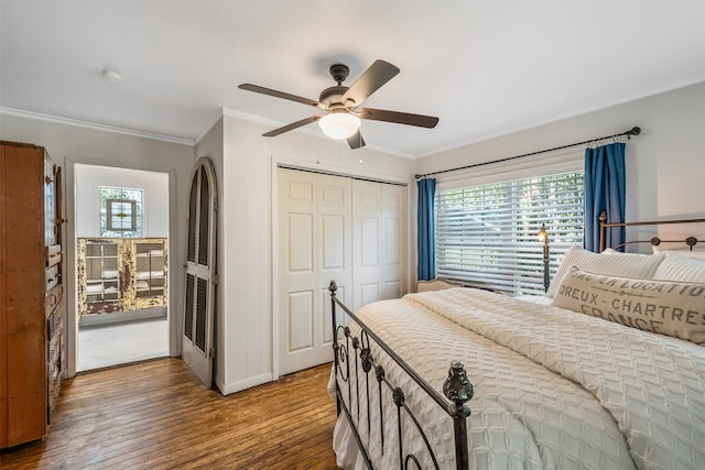 bedroom with ornamental molding, ceiling fan, a closet, and wood-type flooring