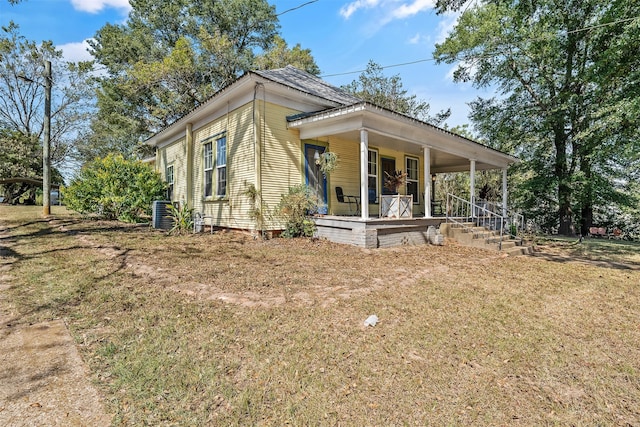 view of front of house with a porch, a front yard, and central AC unit