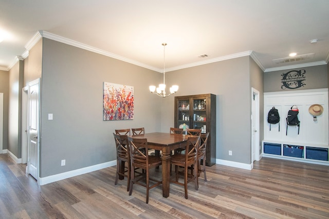 dining area featuring wood-type flooring, crown molding, and a notable chandelier