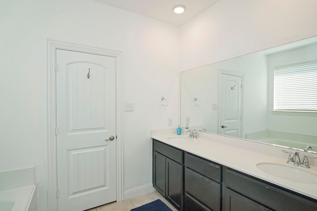 full bathroom featuring double vanity, a garden tub, and a sink