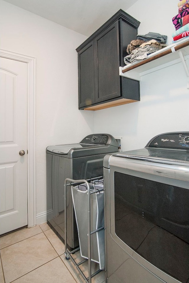 clothes washing area with light tile patterned floors, separate washer and dryer, and cabinet space