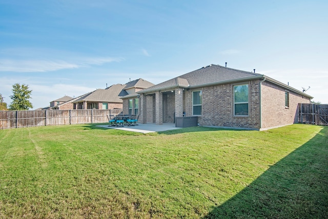 back of property with a yard, a patio, brick siding, and a fenced backyard