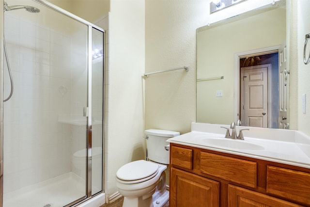 bathroom featuring toilet, vanity, and a shower with shower door