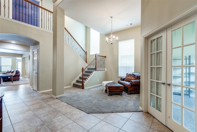 interior space with light tile patterned flooring, a chandelier, and french doors