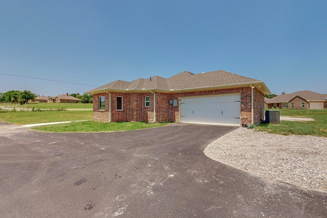 ranch-style house featuring cooling unit, a garage, and a front lawn