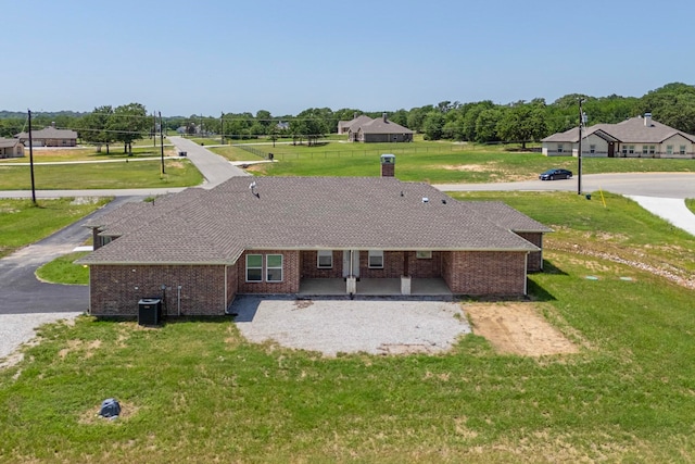 rear view of house featuring cooling unit and a lawn