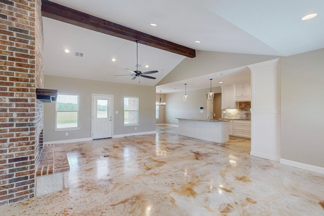 unfurnished living room featuring sink, lofted ceiling with beams, and ceiling fan