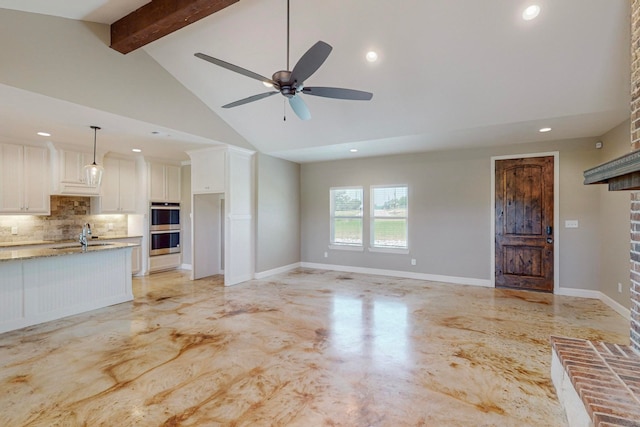 unfurnished living room featuring ceiling fan, high vaulted ceiling, a fireplace, and beam ceiling