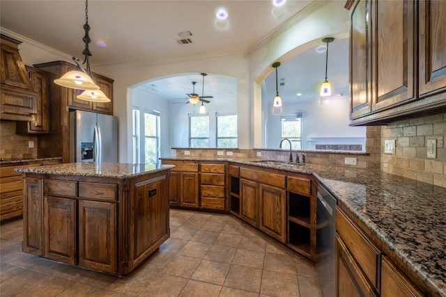 kitchen with stainless steel appliances, arched walkways, a sink, tasteful backsplash, and ornamental molding