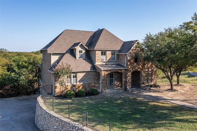 view of front of house with fence, stone siding, and a front yard