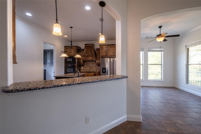kitchen featuring crown molding, dark stone countertops, black appliances, decorative backsplash, and baseboards