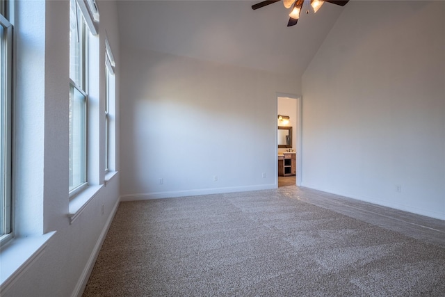 empty room with carpet, a healthy amount of sunlight, high vaulted ceiling, and ceiling fan