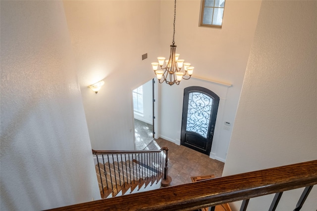 entrance foyer with arched walkways, an inviting chandelier, a towering ceiling, baseboards, and visible vents