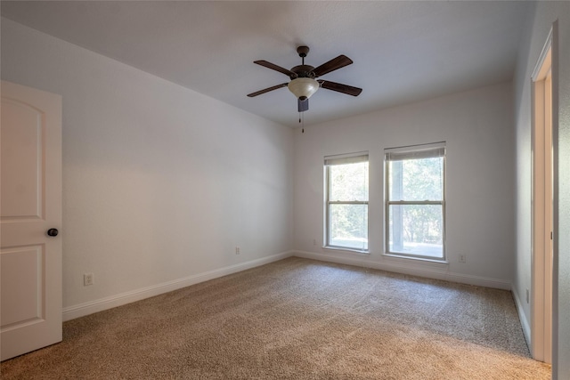 spare room featuring ceiling fan, light carpet, and baseboards