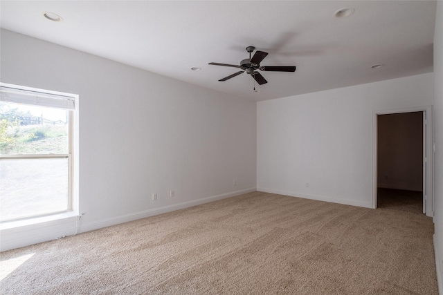 unfurnished room with plenty of natural light, light colored carpet, and ceiling fan