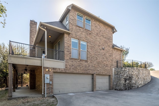 view of home's exterior with a chimney, a balcony, concrete driveway, an attached garage, and brick siding