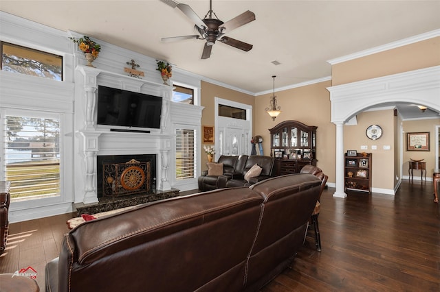 living room featuring ceiling fan, a high end fireplace, decorative columns, dark hardwood / wood-style floors, and ornamental molding