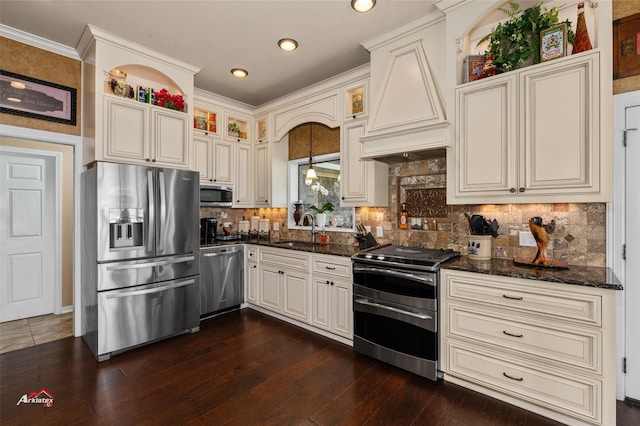 kitchen featuring dark wood-type flooring, dark stone countertops, decorative light fixtures, sink, and stainless steel appliances