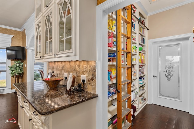 kitchen with dark stone counters, crown molding, and dark wood-type flooring