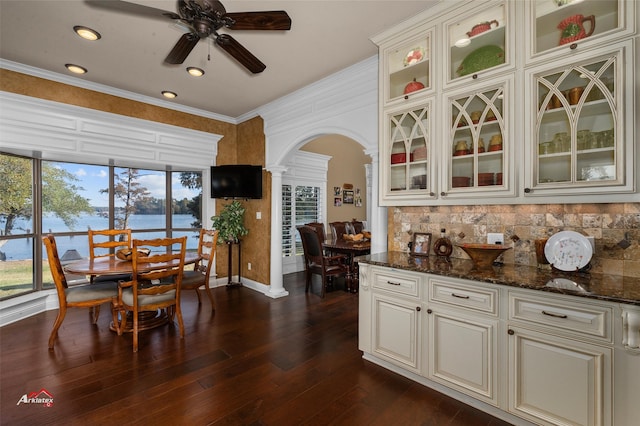 kitchen featuring ornate columns, dark stone countertops, dark hardwood / wood-style floors, and crown molding