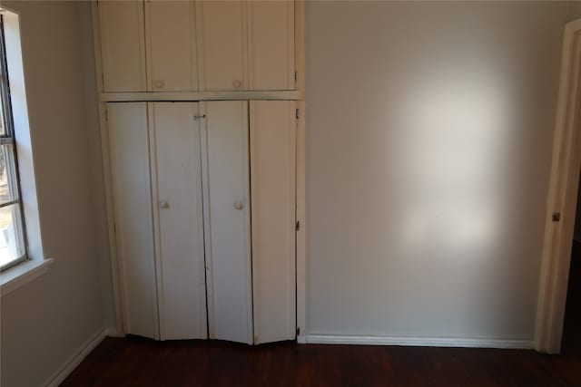 unfurnished bedroom featuring dark wood-type flooring and a closet