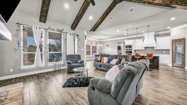 living room featuring a notable chandelier, light wood-type flooring, lofted ceiling with beams, and ornamental molding