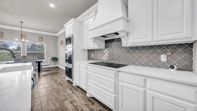 kitchen featuring an inviting chandelier, crown molding, custom range hood, white cabinets, and hardwood / wood-style flooring