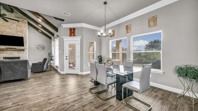 dining room featuring high vaulted ceiling, a stone fireplace, hardwood / wood-style floors, crown molding, and beam ceiling