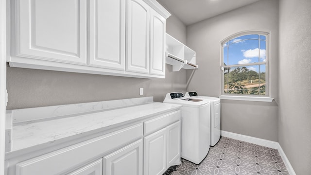 clothes washing area with light tile patterned flooring, independent washer and dryer, and cabinets